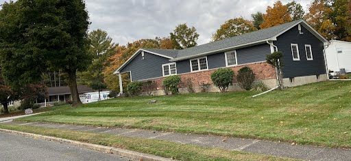 A large house is sitting on top of a lush green hill.