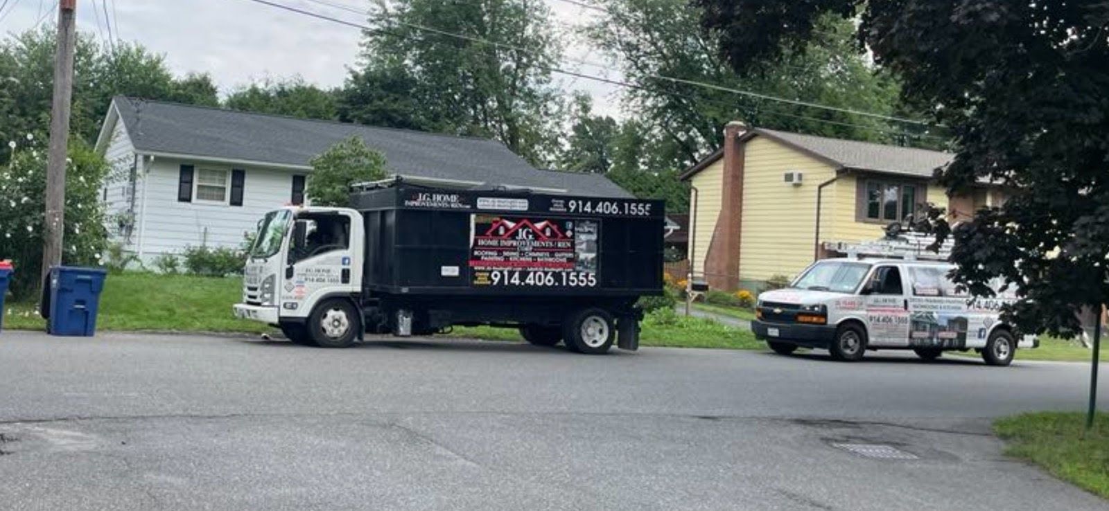 Two trucks are parked on the side of the road in front of a house.