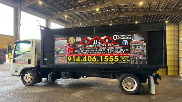Black dump truck with company advertisement; phone number 914.406.1555.
