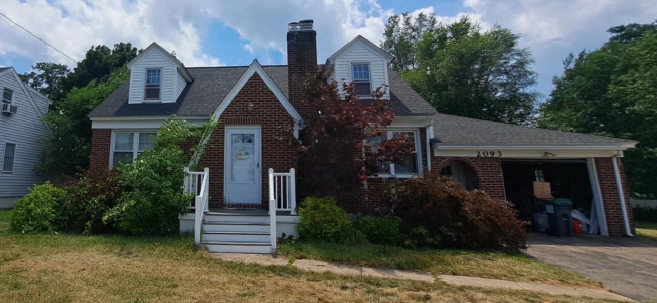 The front of a brick house with a garage and a chimney.