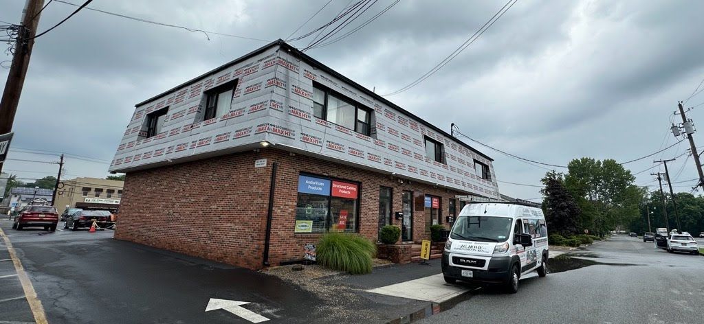A white van is parked in front of a brick building.