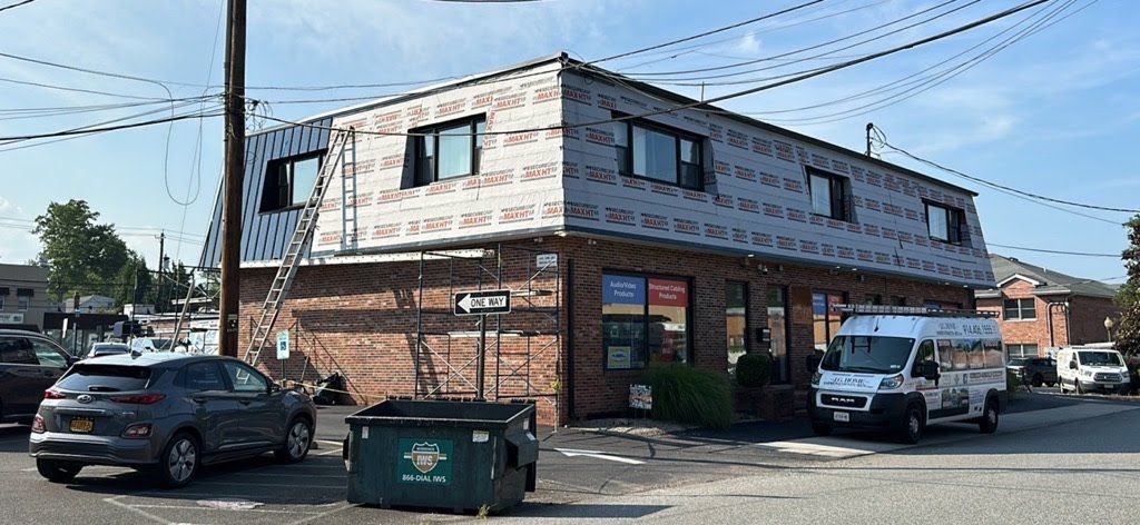 A building with cars parked in front of it and a dumpster in front of it.
