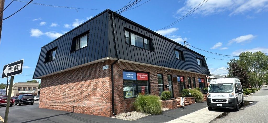 A brick building with a black roof and a white van parked in front of it.