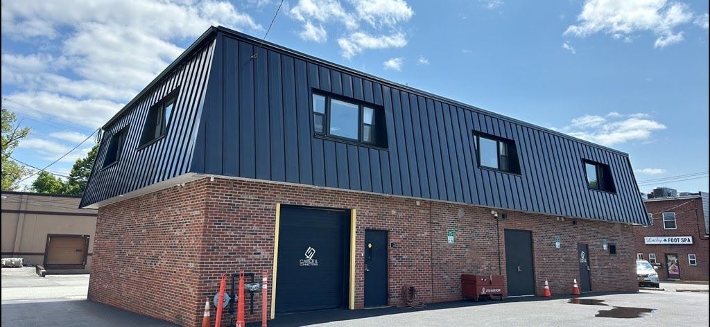 A large brick building with a black roof and a lot of windows.