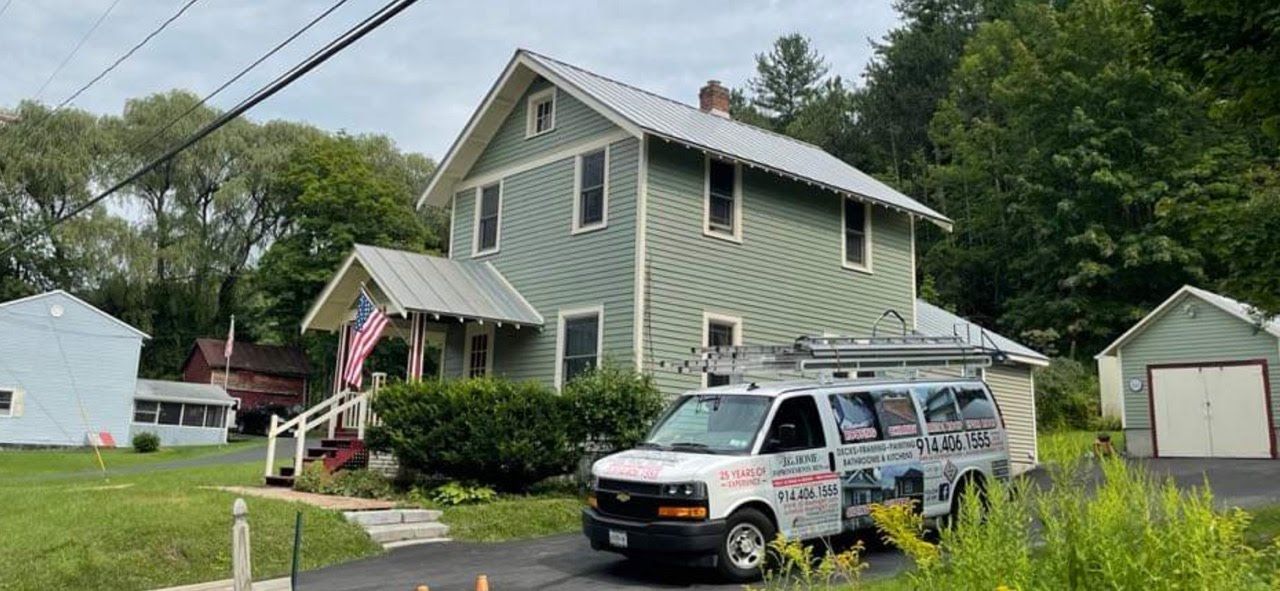 A white van is parked in front of a green house.