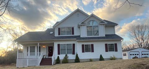 A large white house with a black roof and a large porch.