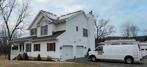A white van is parked in front of a large white house.