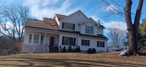 A large white house is sitting on top of a grassy hill.