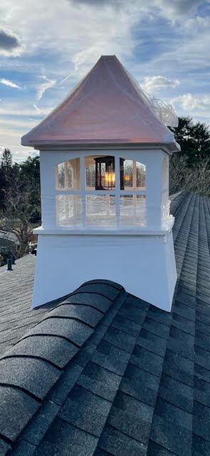 A white chimney on top of a roof with a copper roof.