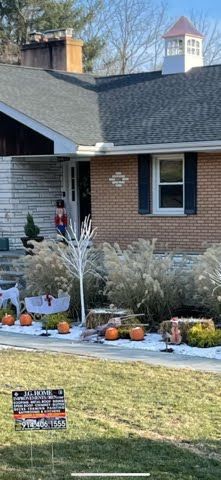 A brick house decorated for halloween with pumpkins and a christmas tree.