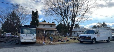 Two white vans are parked in front of a house.