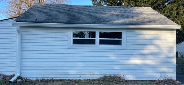 A white house with a gray roof and two windows.