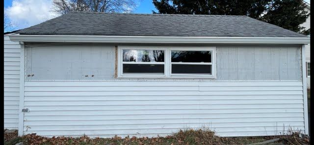 A white garage with a window on the side of it.