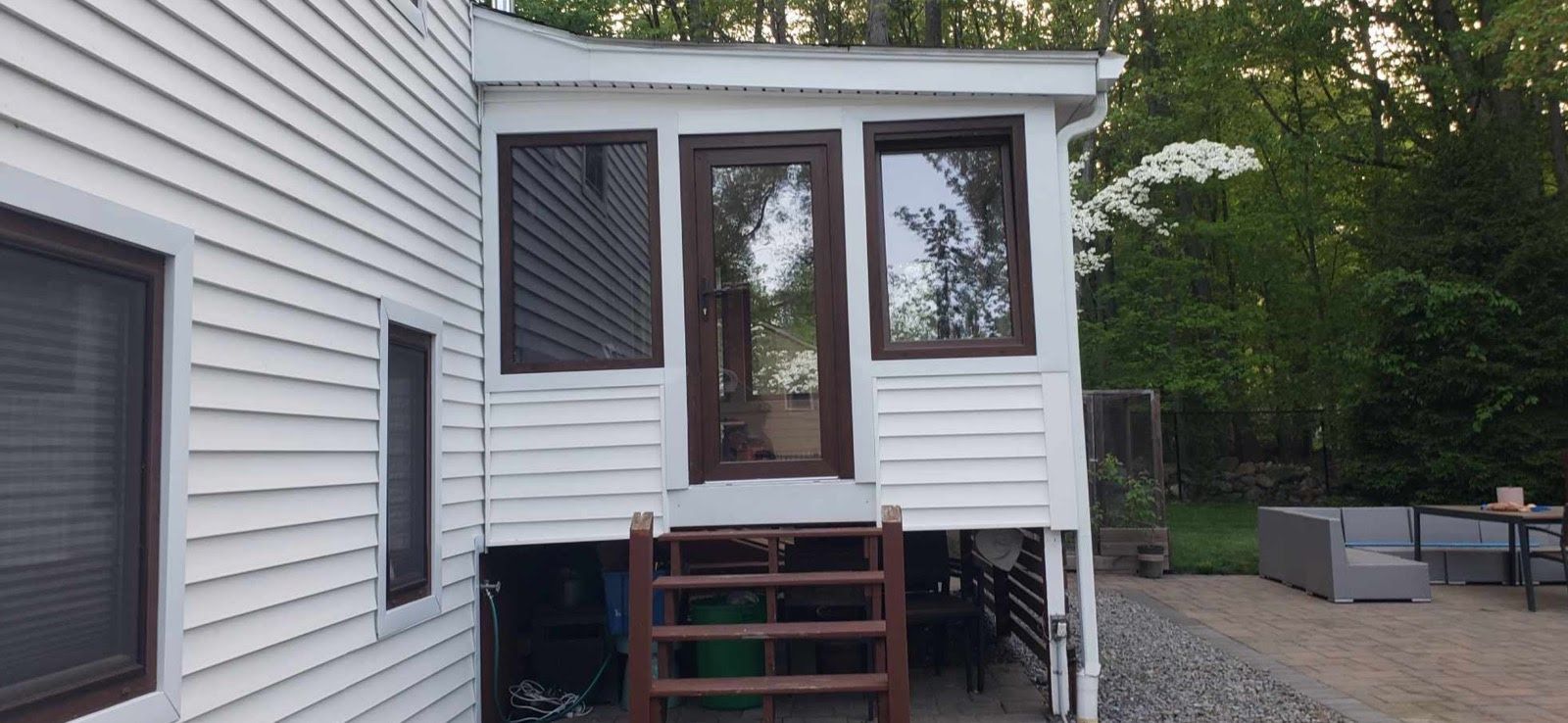 A white house with a screened in porch and stairs leading to it.