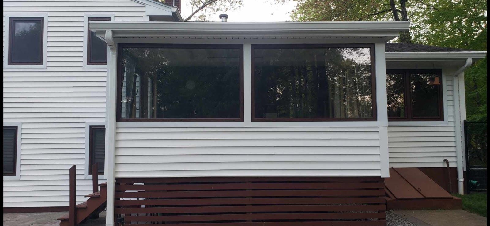 A white house with a screened in porch and stairs.