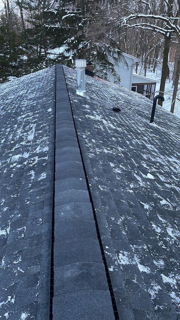 A roof with snow on it and trees in the background.