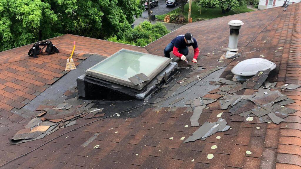 A man is working on a roof with a skylight.