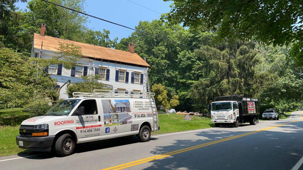 Two trucks are parked on the side of the road in front of a house.
