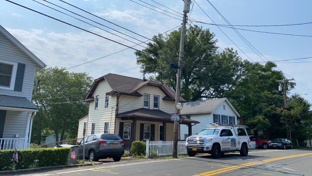 A white truck is parked on the side of the road in front of a house.