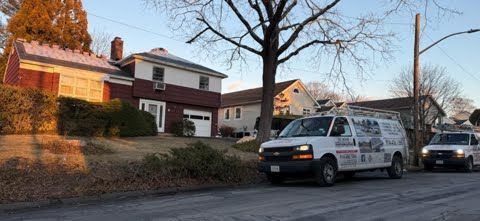 Two white vans are parked in front of a house.