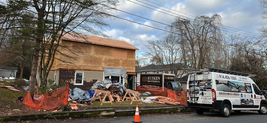 A white van is parked in front of a house under construction.