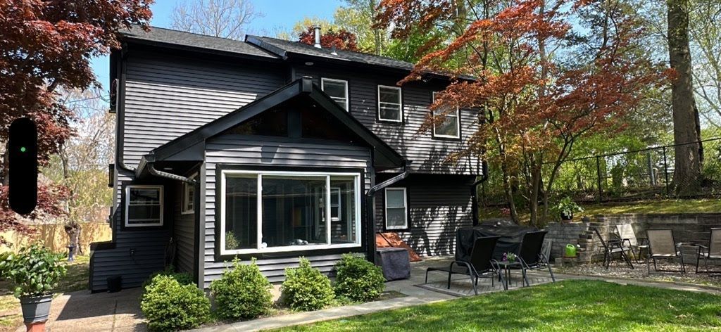 A large black house with a large lawn in front of it.