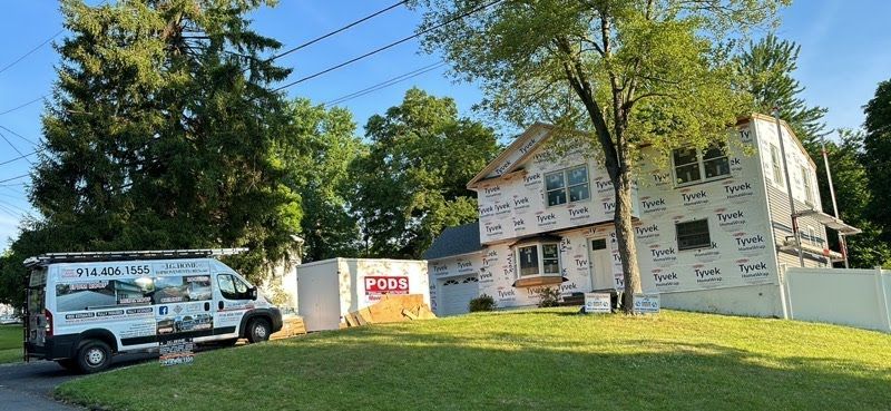A white van is parked in front of a house under construction.