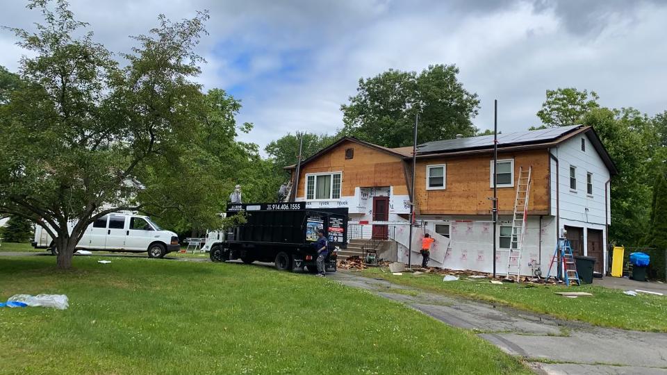 A house is being painted and a truck is parked in front of it.