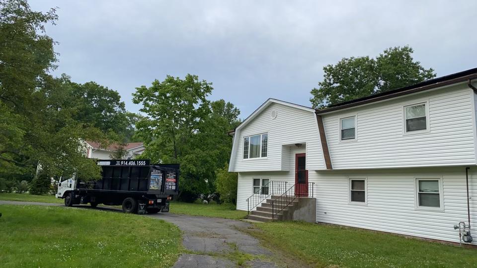 A black dump truck is parked in front of a white house.