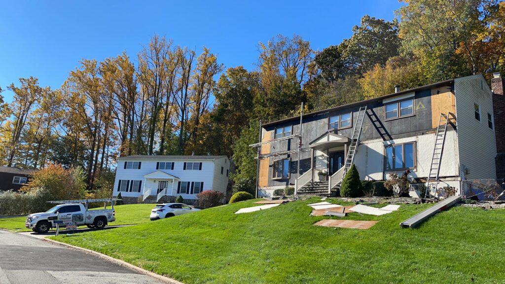 Two houses are sitting on top of a lush green hillside.