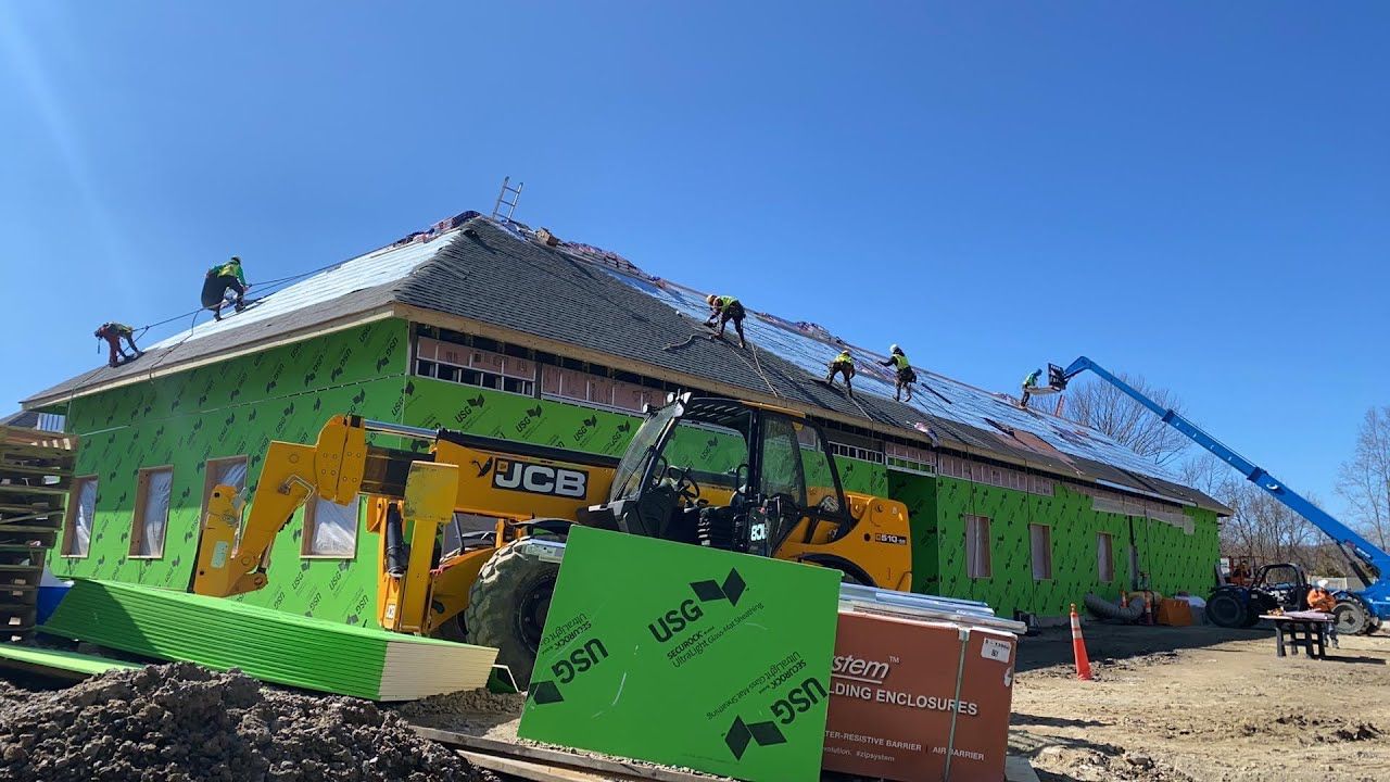 A group of construction workers are working on the roof of a building.