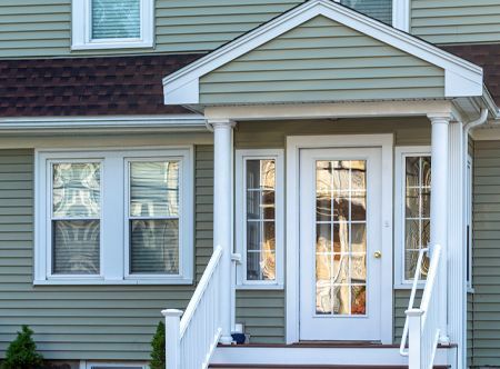 Green house exterior with white trim, front door, and windows. Brown roof.