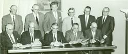 A group of men in suits and ties are sitting around a table.