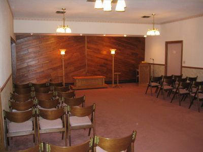 A room with rows of chairs and a wooden wall