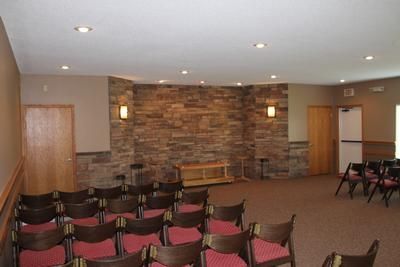 A room with rows of chairs and a stone wall