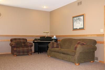 A living room with a couch , chair , and piano.