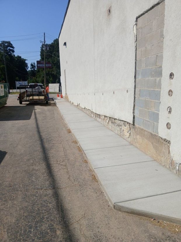 Concrete ramp alongside a building with a block-filled doorway. A trailer is parked near the road.