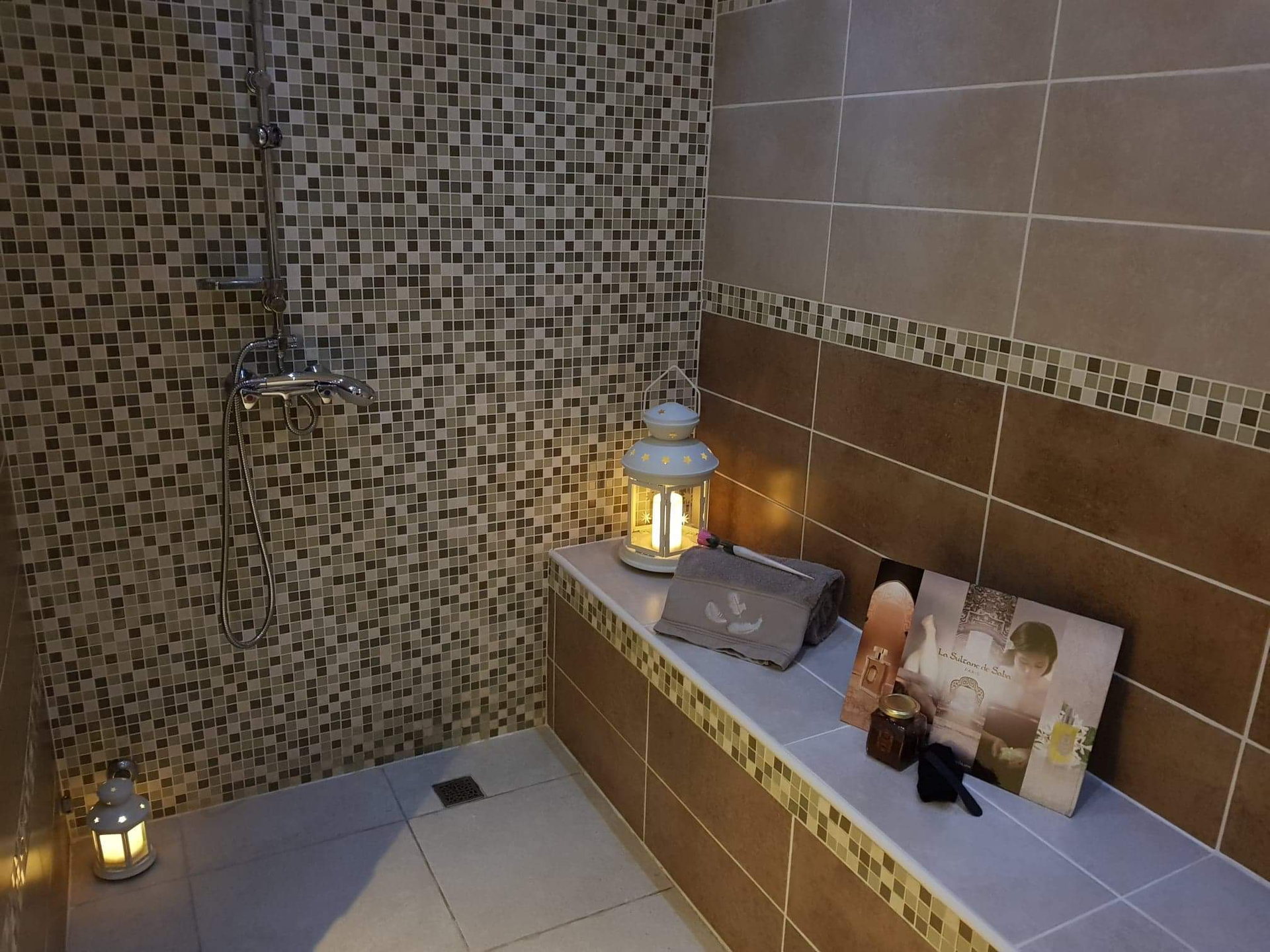 Une salle de bain avec une douche et une étagère avec des bougies dessus