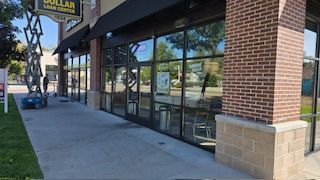 Dollar Loan Center storefront with large windows, brick and tan accents. Sidewalk in front.