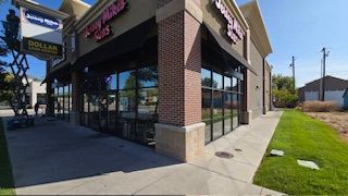 Exterior of a brick building with large windows and awnings.  Dollar General and 