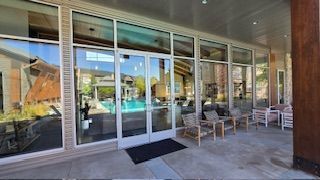 Exterior of a building with glass windows and doors; pool visible through the glass.