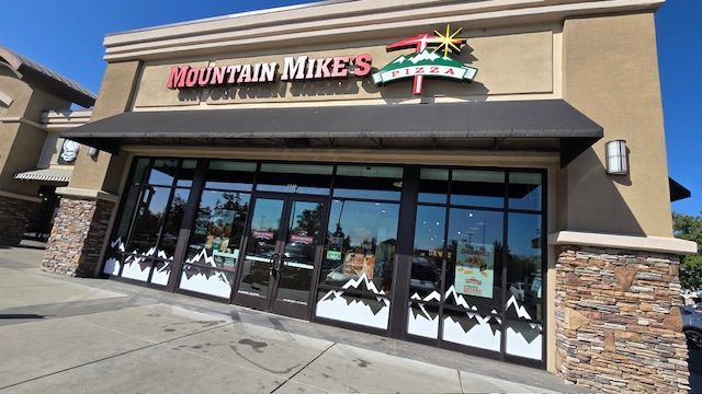 Mountain Mike's pizza restaurant with large windows, black awning, and mountain logo.