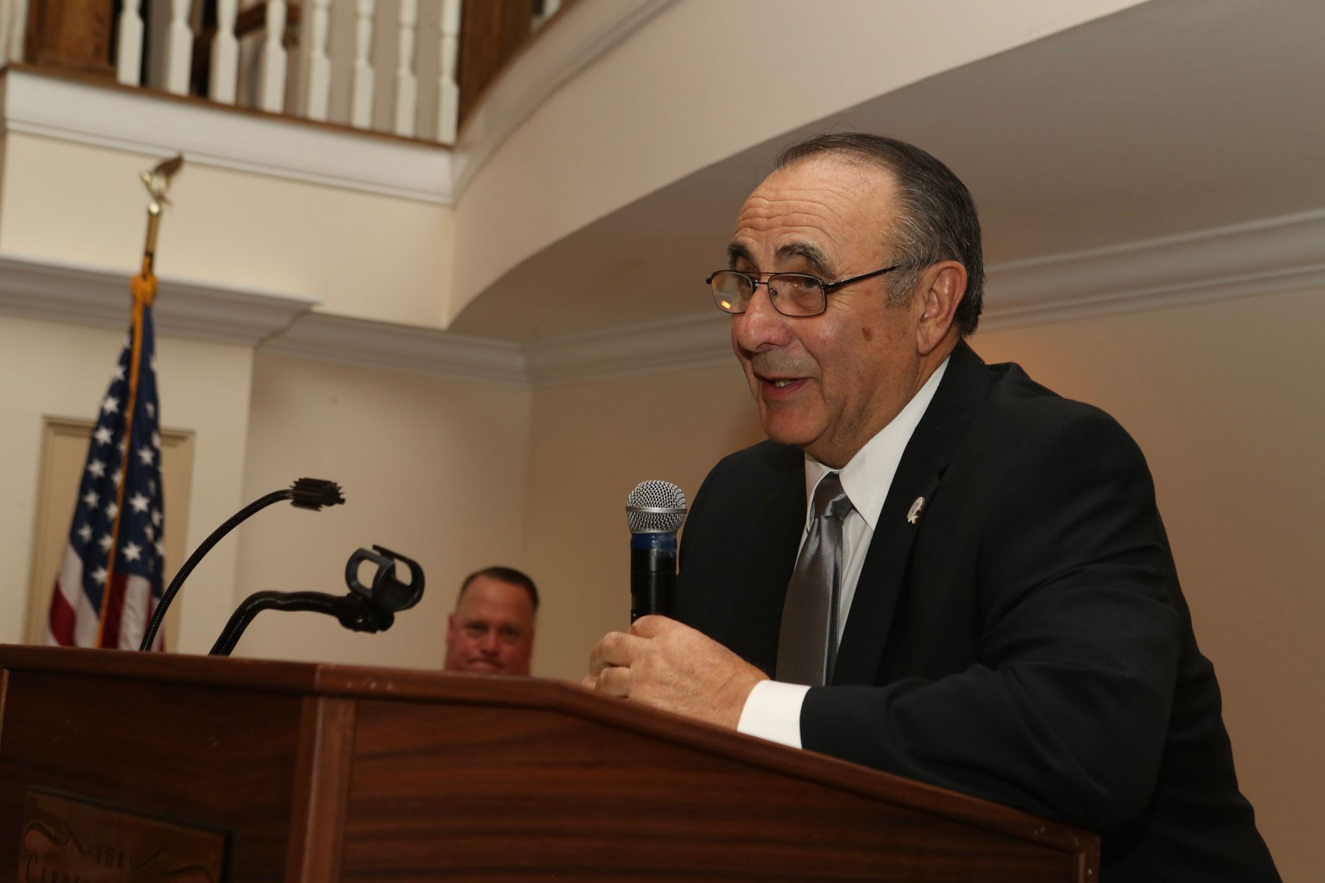 a man in a suit and tie is speaking into a microphone
