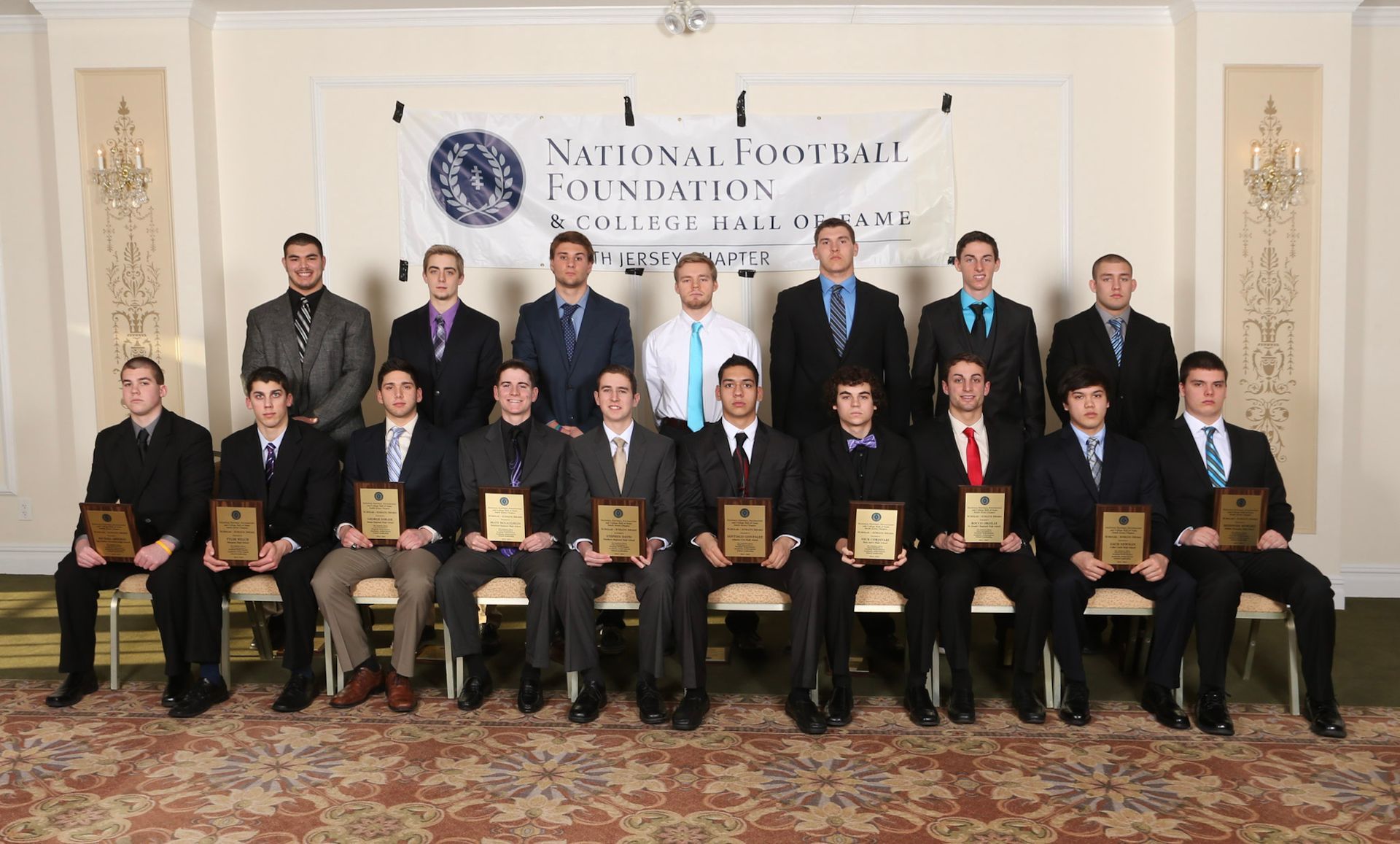 a group of men are posing for a picture in front of a national football foundation banner