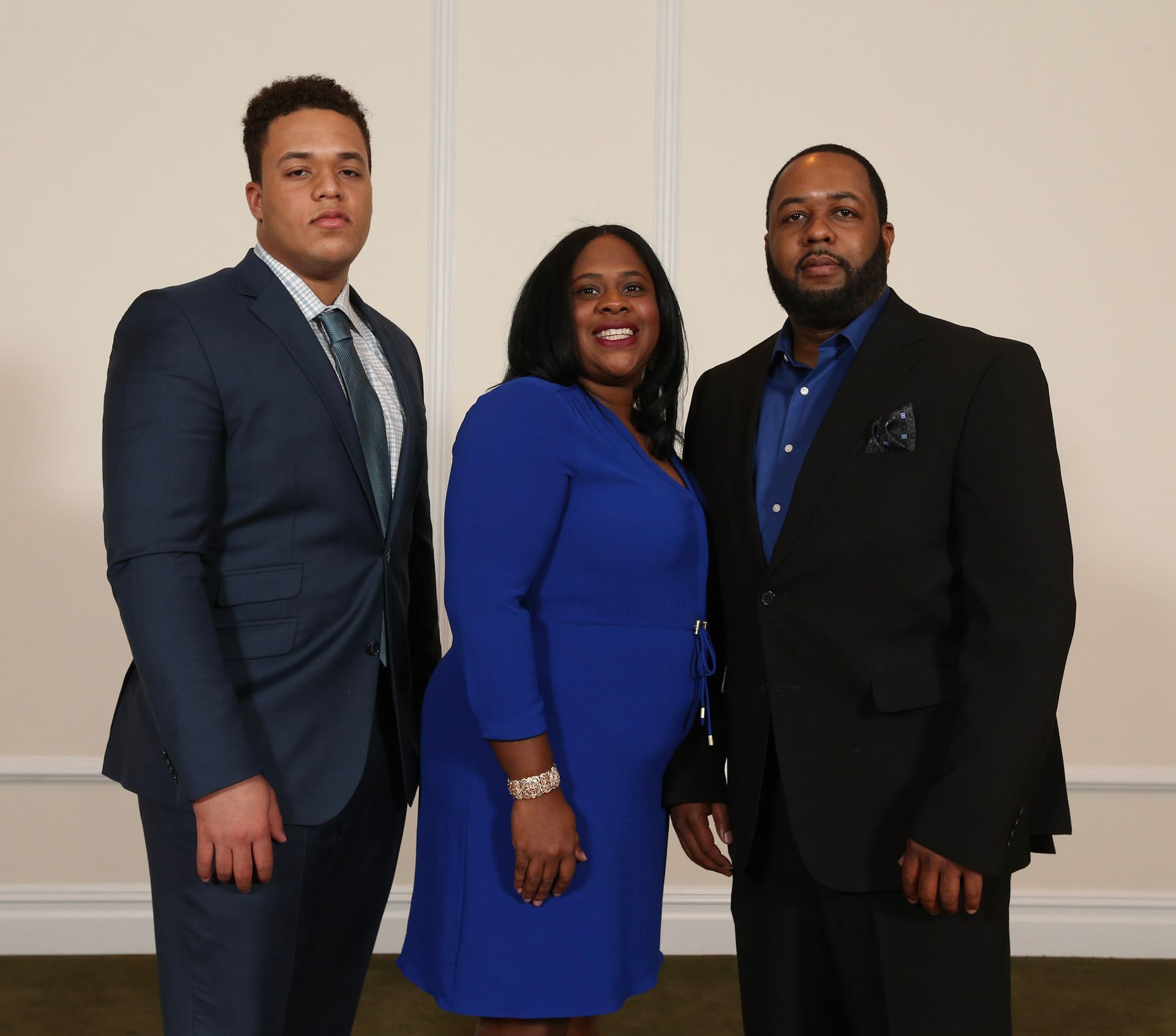 a man in a suit stands next to a woman in a blue dress
