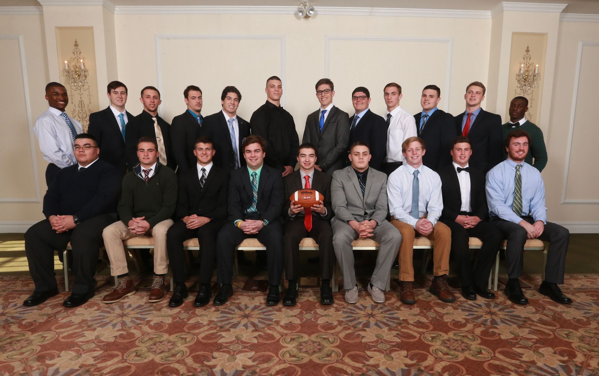 a group of men posing for a picture with one man holding a football