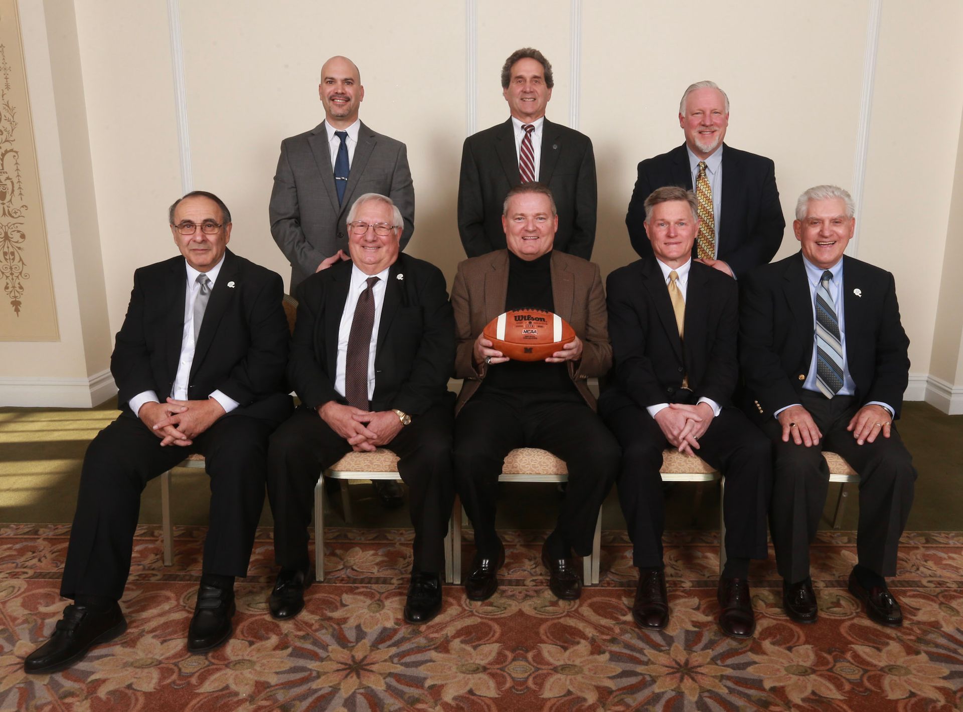 a group of men posing for a picture with one man holding a football