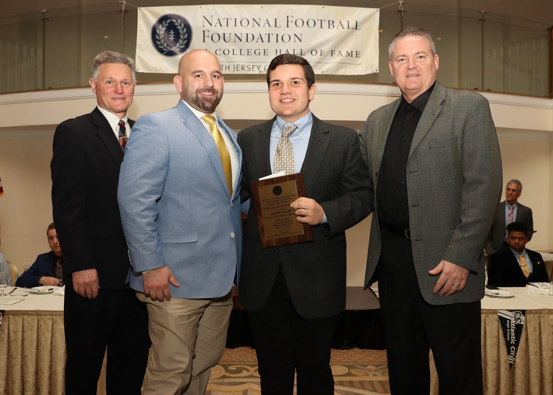 a group of men standing in front of a national football foundation banner