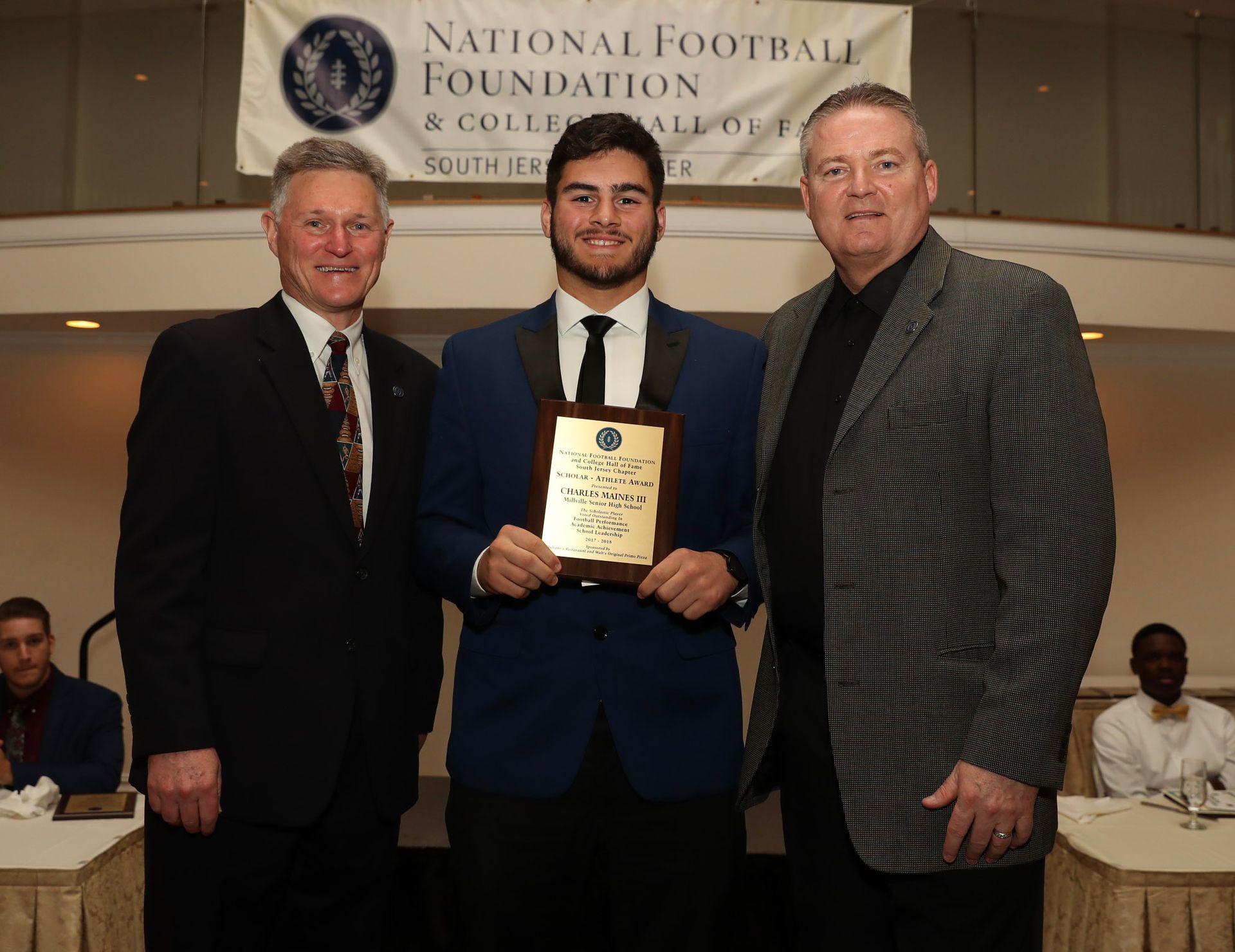 three men standing next to each other with a national football foundation banner behind them