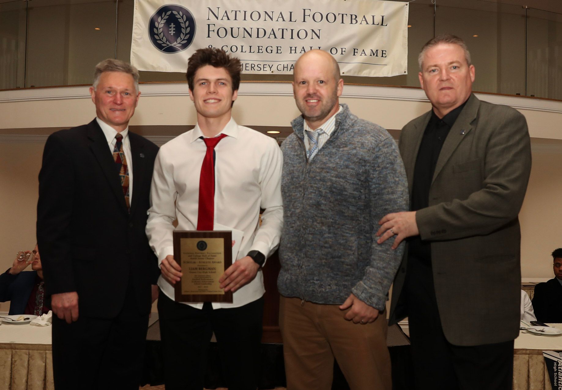 a group of men are posing for a picture in front of a national football foundation banner